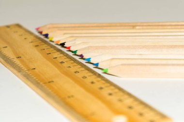 Beyaz arkaplanda altıgen şekilli kalem rengi ve ahşap cetvel.