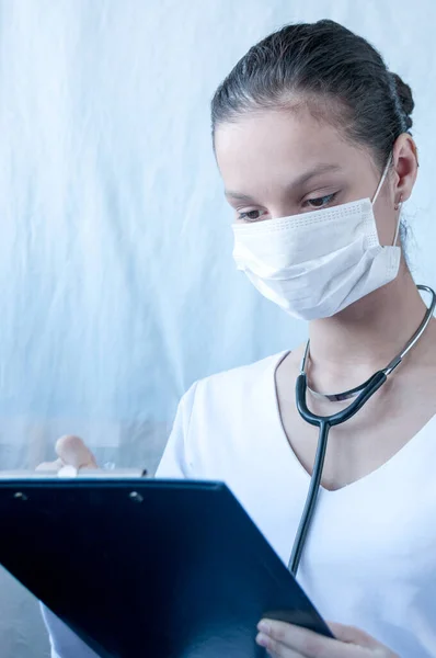 Girl doctor in mask writes prescription for treatment