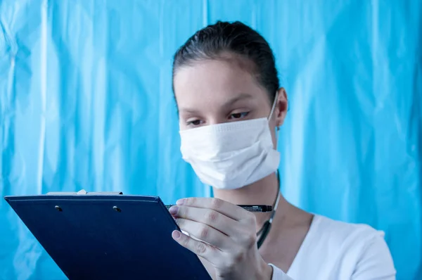 Maskeli kız tedavi için reçete yazıyor