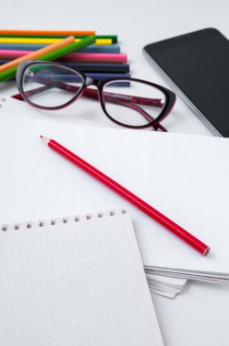 İş hayatı, gözlük, akıllı telefon, defter ve renkli kalemler.