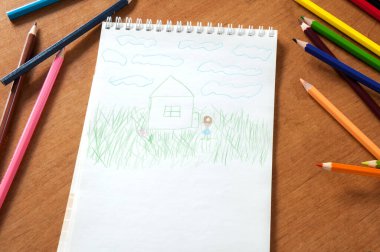 Masadaki çocukların çizimlerine ve renkli kalemlere.
