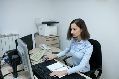 Ofisteki bilgisayarın başında çalışan esmer kız.