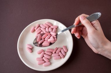 Tabletlerle dolu bir tabak ve kahverengi arka planda bir kaşık.