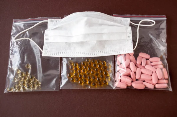 Tablets and vitamins, fish oil in plastic packaging and medical mask on a brown background
