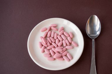 Kahverengi arka planda tablet ve kaşık.