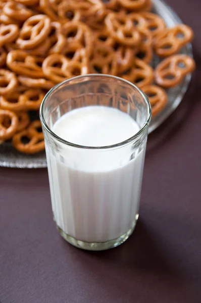 Ett Glas Mjölk Och Pretzel Cookies Transparent Platta Brun Bakgrund — Stockfoto