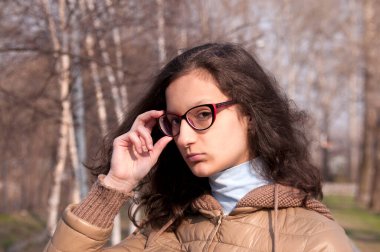 Esmer bir kız ellerini bardaklarına dayar ilkbaharda parkta.