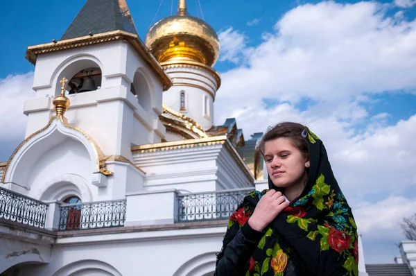 Girl near the church holds his arms