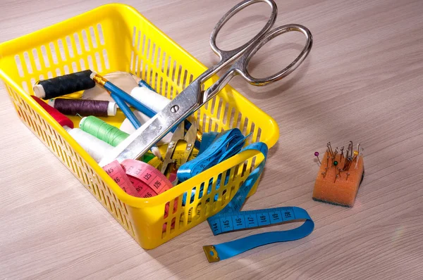 On the table is a basket of tools for sewing