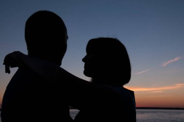 Günbatımı arka planında kadın ve erkeğin silueti.