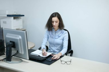 Esmer kız ofisteki bir deftere not alıyor.