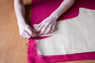 Kadın eli, masadaki kırmızı bir bezin üzerinde küçük bir kağıt izi bırakır.