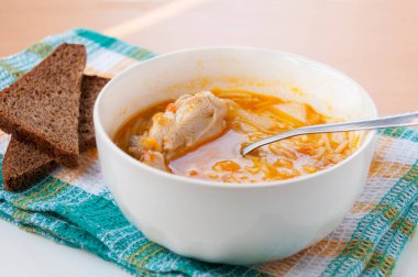 Makarnalı tavuk çorbası ve havlunun üstünde kahverengi ekmek.