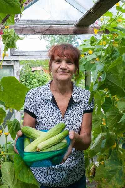 Serada dururken elinde salatalık tutan mutlu bir emekli.