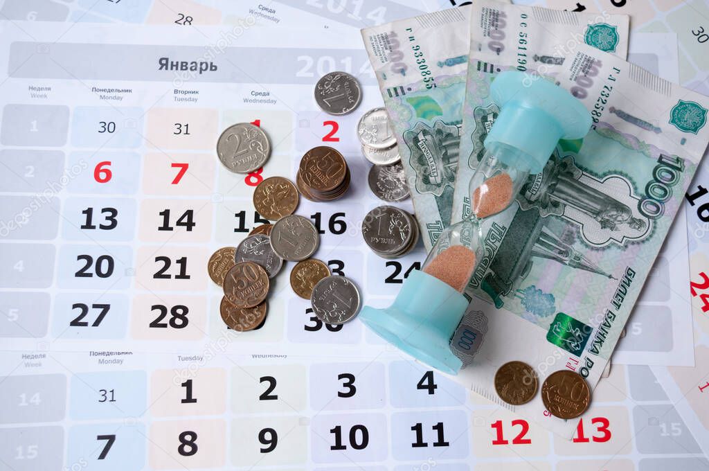 Hourglass and money lie on calendar sheets