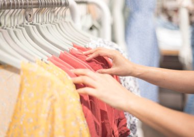 Alışveriş merkezindeki kumaş mağazasının rafında işaretli desenli pamuk elbise seçen kadın eli. Giyim ürünlerinin fiyatını, indirimini ve tanıtımını kontrol et.