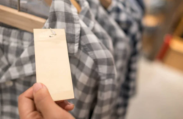 Hand Hält Unbeschriebenes Papier Preisschild Von Kariertem Muster Baumwollhemd Auf — Stockfoto