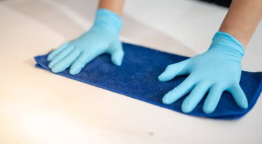 Erkek el ameliyat eldiveni giyer çelik tahtaya temizlik yapmak ve toz süpürmek için kumaşla ovalarken.