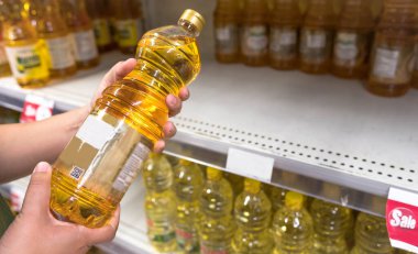 BANGKOK, THAILAND- 15 Mart 2020: Süpermarkette yiyecek stoklamak için Panik Alıcı Coronavirus Covid-19 konsepti olan petrol şişesi ve boş petrol rafları tutan kadın. 