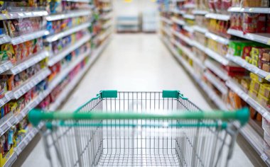Süpermarket koridorunda boş gümüş ve yeşil alışveriş arabasıyla bulanık etki, Süpermarkette yiyecek istiflemek için Panik Alıcı, Coronavirus Covid-19 konsepti,.