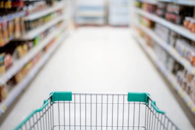 Süpermarket koridorunda boş gümüş ve yeşil alışveriş arabasıyla bulanık etki, Süpermarkette yiyecek istiflemek için Panik Alıcı, Coronavirus Covid-19 konsepti,.