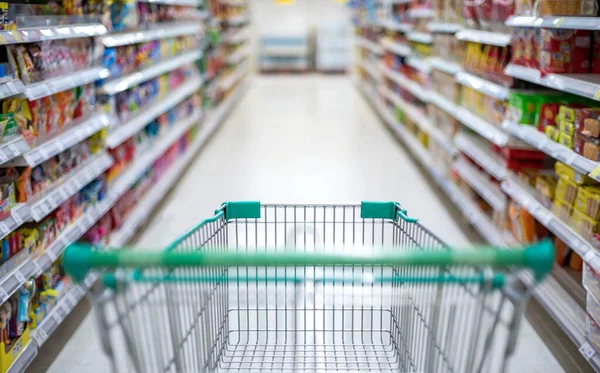 Süpermarket koridorunda boş gümüş ve yeşil alışveriş arabasıyla bulanık etki, Süpermarkette yiyecek istiflemek için Panik Alıcı, Coronavirus Covid-19 konsepti,.