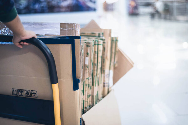 Мужская рука толкая коричневую коробку положить на коробку тележку для доставки, рабочий собирает картонные коробки и посылки
