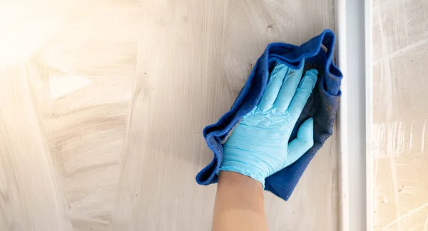 Male hand wear surgical glove while rubbing with the cloth  for cleaning and sweeping dust on the steel board.