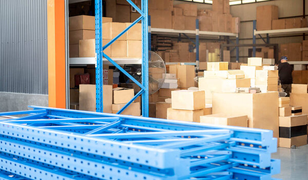 Голубые металлические стойки готовятся к сборке на складе или складе и полках для укладки картонных коробок изделий
.