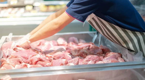 The supermarket employee preparing the Fresh pork meat slice on display tray for consumers select in a supermarket. The high quality for cooking in home.