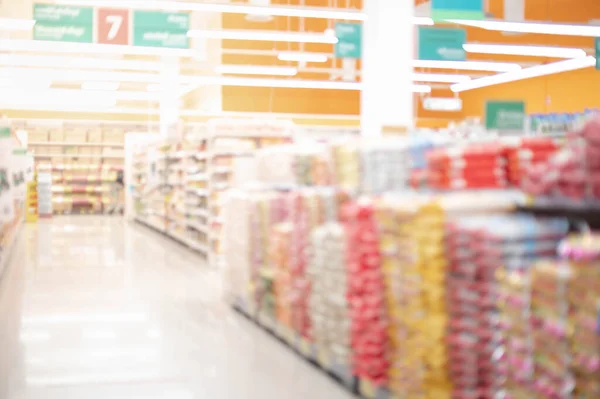 Abstract blurred supermarket aisle with rice bag of  shelves and many goods of food prepare for shopper buy for hoarding use in everyday at the supermarket.