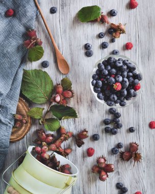 Yaz hala hayattır. Şeffaf bir kasede böğürtlen vardır. Yabanmersini ve ahududu, arka planda bir kutu fındık. Hafif arkaplan. Çiftçi. Hasat et. Faydalı bir ürün. Vejetaryen. Sağlıklı yemek..