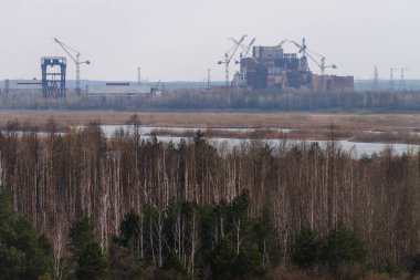 Ufuktaki Çernobil Nükleer Santrali 'nin bitmemiş binasının görüntüsü terk edilmiş ve Çernobil Bölgesi' nde kıyametin koptuğu yer.