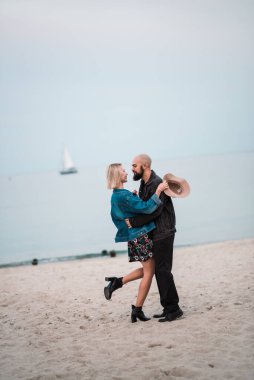 Mutlu genç çift kumsalda el ele tutuşarak eğleniyor..