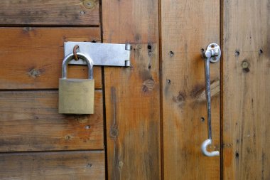 20 Ekim 2019, Leeds, İngiltere. Ahşap bahçe kulübesi kapısı, pirinç kilit ve çelik tokayla korunuyor. Kilidin sağında bir kanca askısı asılı.