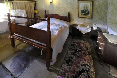 19 Ağustos 2018, Viktorya dönemi yatak odası, Ryedale Açık Müzesi, Yorkshire, İngiltere. Arka duvarda Kraliçe Victoria 'nın bir resmi asılı ve tuvalet masasında bir yatak ısıtıcı, su sürahisi ve iki bardak var..