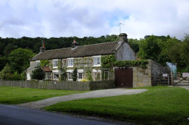 19 Ağustos 2018: Ryedale Halk Müzesi, Hutton le Hole, Kuzey Yorkshire, İngiltere. Üç teraslı, taştan yapılmış, tahta çatılı kır evleri, her birinin ön bahçeleri ahşap çitlerle çevrili.