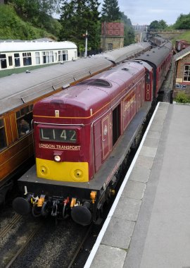 17 Aug 2018, sınıf 20 dizel elektrikli lokomotif, Londra Ulaşım Ahırı 'nda, Goathland' a varır, demiryolu meraklılarının trenini taşır. Buharlı bir lokomotif bitişikteki raydan kalkmak için bekliyor