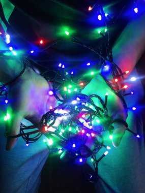 Bir adamın ellerinde çok renkli çelenkler.