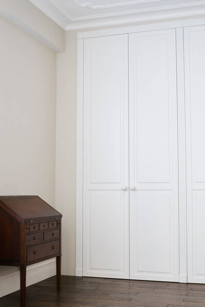 White cabinet doors with brown floor handles and a brown chest of drawers