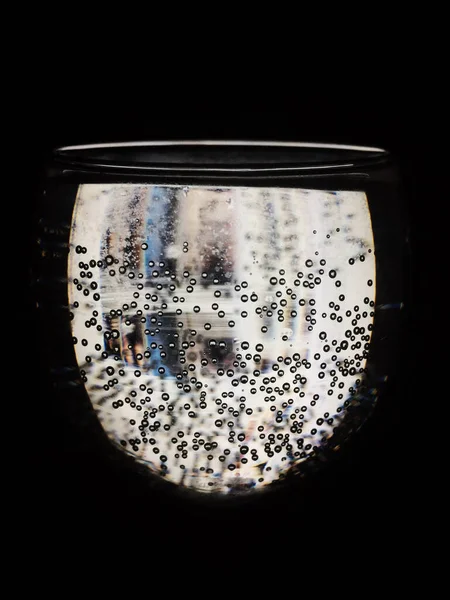 Siyah arka planda ışığın geçtiği kabarcıklı bir bardak.