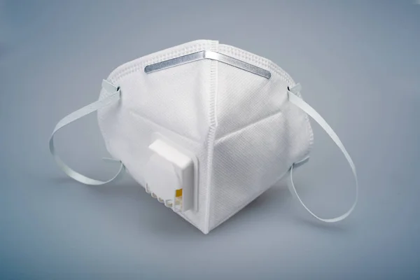 A white N95 mask with a breathing valve against a gray background