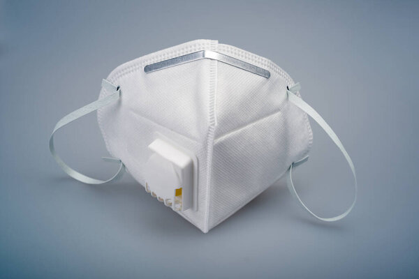 A white N95 mask with a breathing valve against a gray background