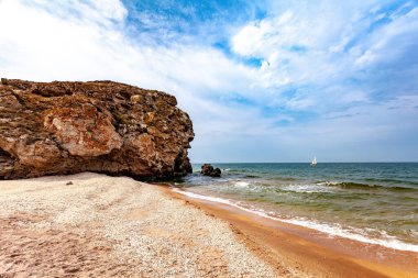 Azov Denizi 'nin panoramik manzarası. Kumsal, rock. Denizin turkuaz suyunda beyaz bir gemi. Boşluğu kopyala.