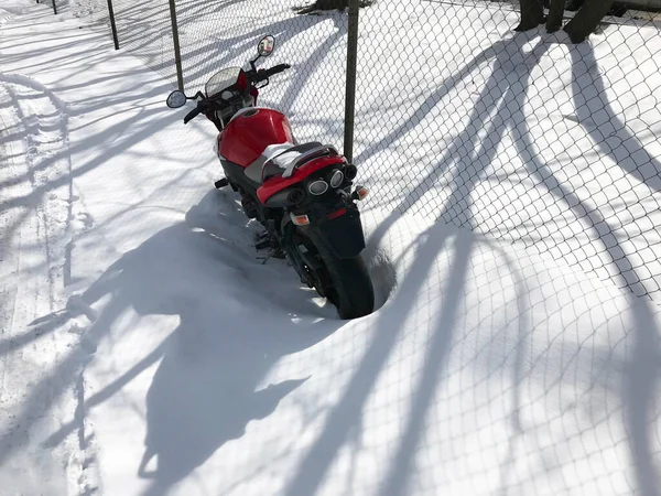 Röd motorcykel står på en snöig parkeringsplats täckt av snö på vintern — Stockfoto