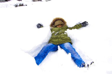 Çocuk kar üzerinde uzandı ve kar kışın keyfini çıkarın.