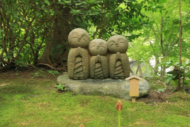 Japonya 'nın Kamakura kentindeki Hase-Dera tapınağında küçük bebek bütçe heykelleri taze yeşille çevrili.