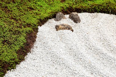 Bahçe zemini küçük taşlar ve yeşil otlardan oluşur..