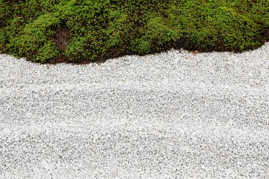 Bahçe zemini küçük taşlar ve yeşil otlardan oluşur..