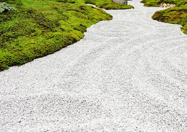 O piso do jardim é composto por pequenas pedras e grama verde . — Fotografia de Stock